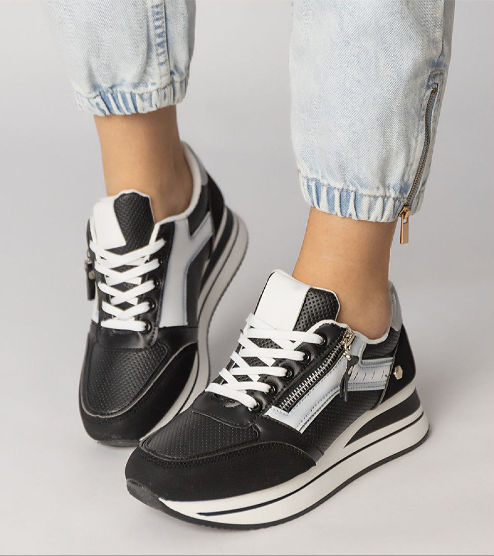 Vorelle Zip-Up Sneakers in black with decorative side zipper, crafted from synthetic leather, pictured with a casual outfit.
