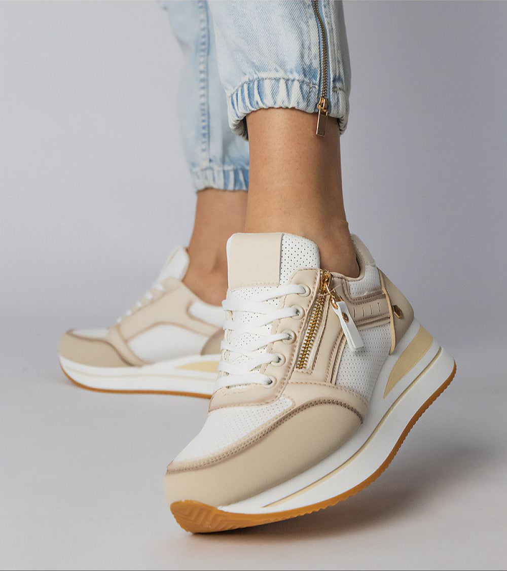 Beige and white zip-up sneakers with decorative side zipper and elevated platform, paired with light blue jeans.