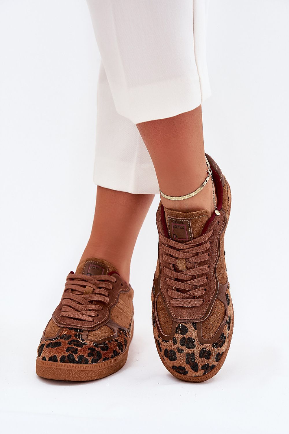 Leopard print suede sneakers paired with white pants, showcasing stylish footwear for urban outfits.