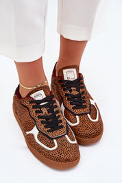Leopard print sneakers with black laces, worn by a person in white pants, showcasing casual style and urban fashion.