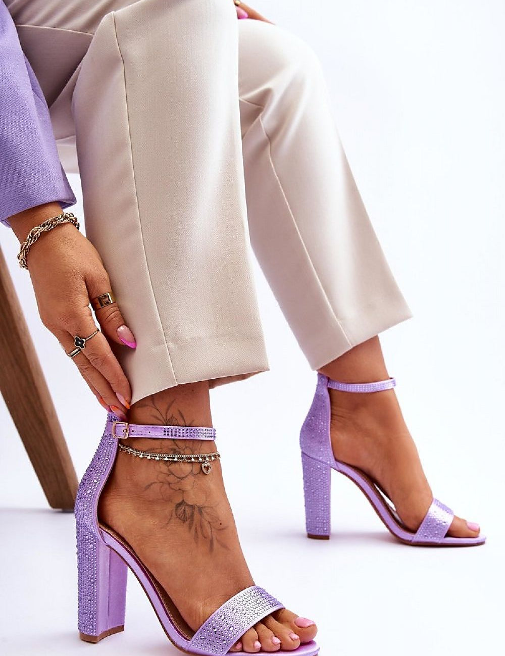 Woman wearing Elryne Satin Heel Sandals with ankle straps and post-style heels in light purple, paired with beige trousers.