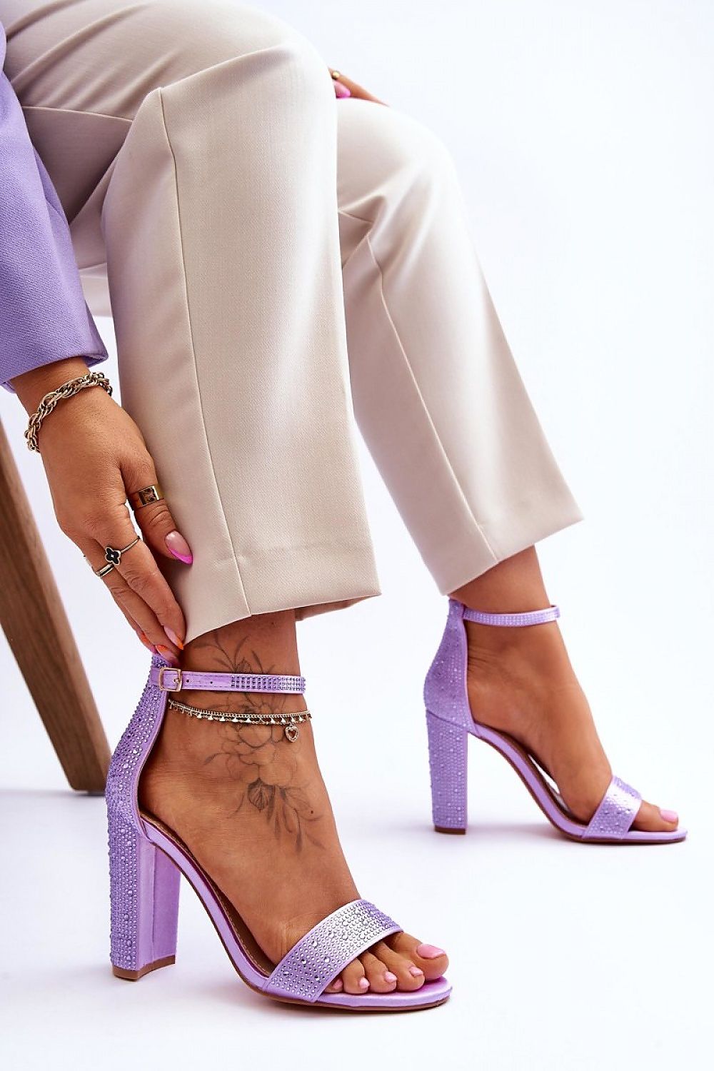 Woman wearing Elryne Satin Heel Sandals with ankle straps and post-style heels in light purple, paired with beige trousers.