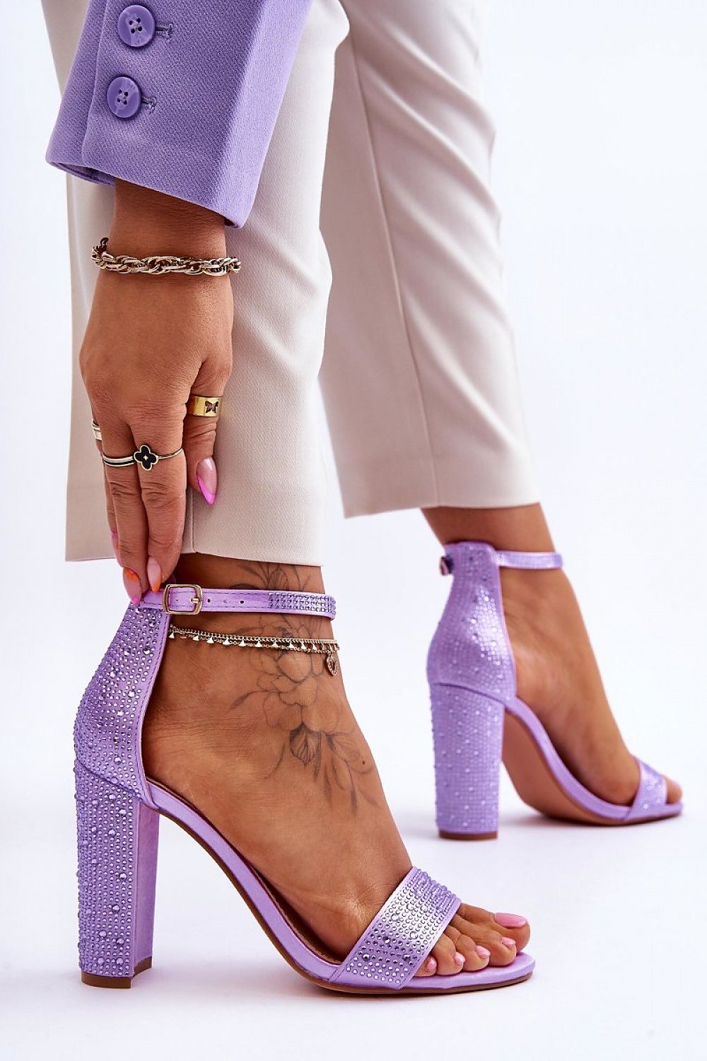 Woman wearing purple satin heel sandals with ankle strap and rounded open toe, styled with chic outfit for formal occasion.