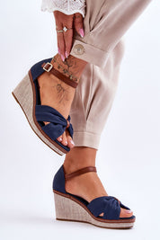 Larvella woven fabric buskins with buckle ankle strap, non-slip sole, and sculpted heel in blue, worn with beige trousers.