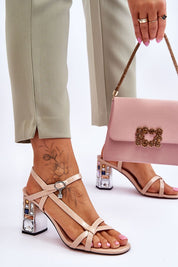 Woman wearing Carinea High Heel Sandals with eco leather straps and jeweled stiletto, holding a pink handbag with floral design.