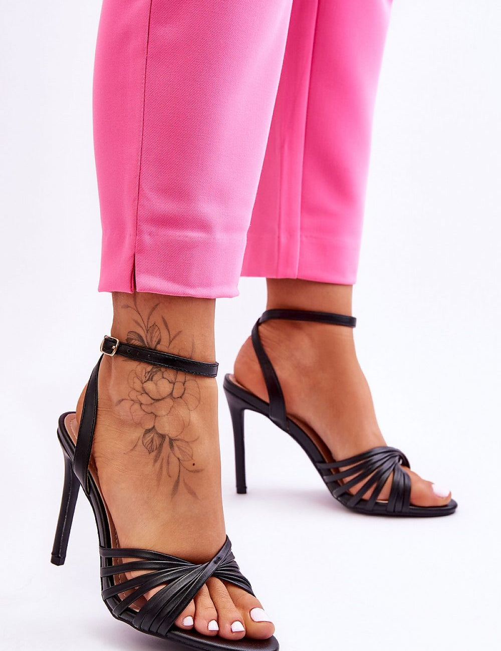 Woman wearing Astella Strappy Tie-Up Heels with pink pants, showcasing elegant design and stiletto heel.