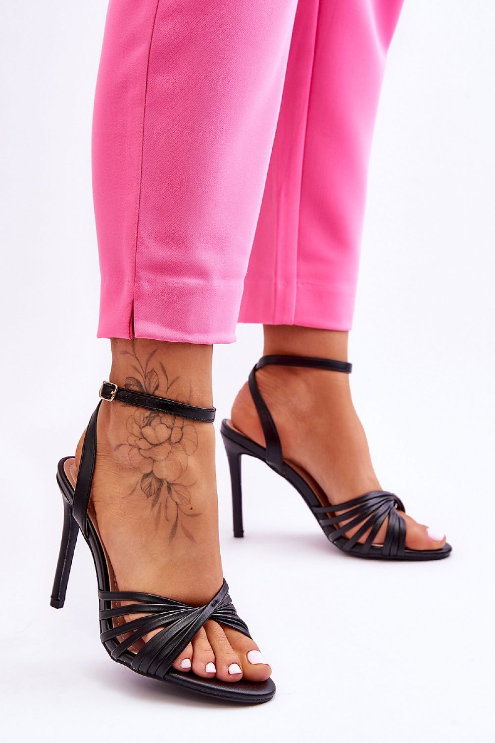 Woman wearing Astella Strappy Tie-Up Heels with pink pants, showcasing elegant design and stiletto heel.