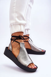 Woman wearing Liavone Leather Lace-Up Sandals in metallic silver with ankle-high design and platform heel for style and comfort.