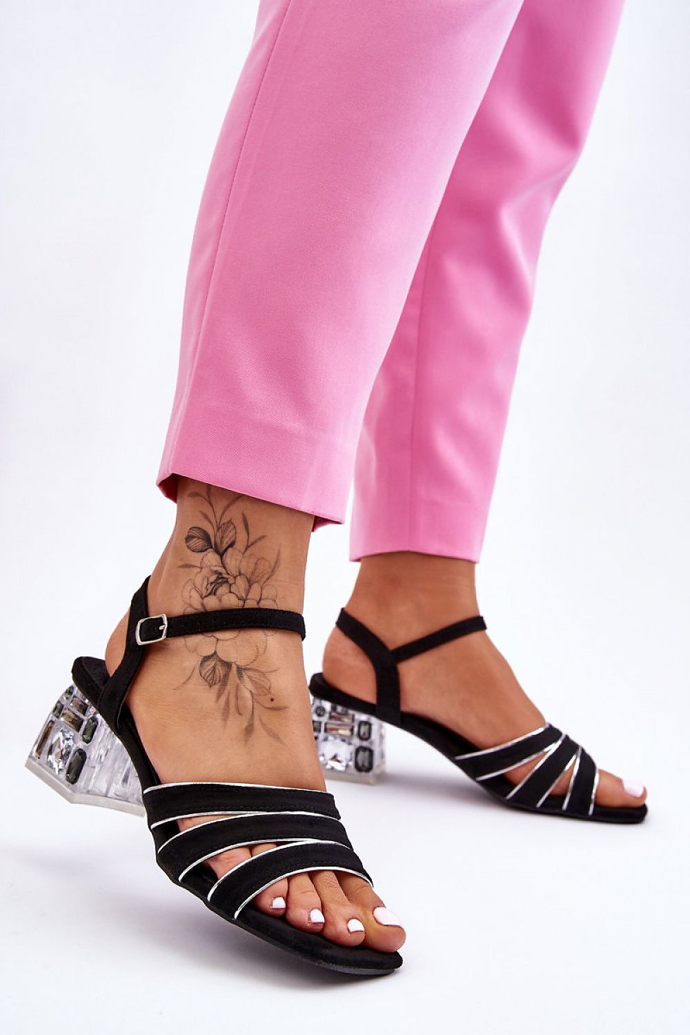 Woman wearing Arnevie suede block heel sandals with embellished heel and open square toe, paired with pink pants.