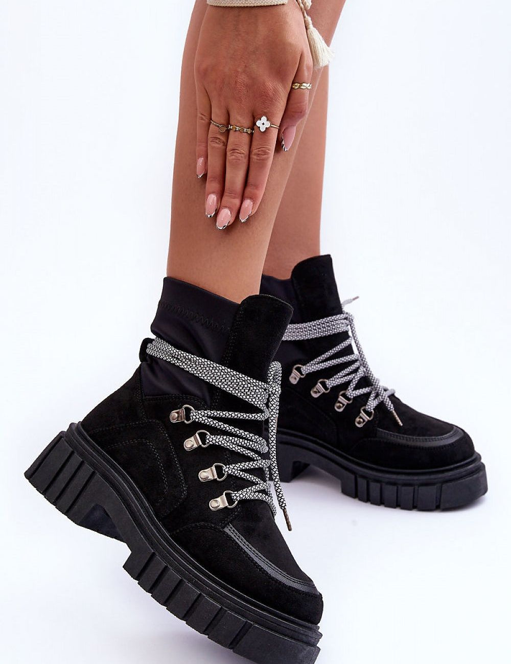 Black eco-suede chunky heel ankle boots with silver laces and a platform sole, perfect for winter fashion, shown on a model's feet.