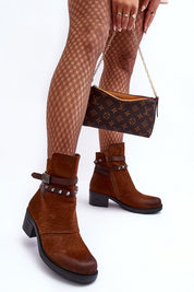 Model wearing brown ankle boots with patterned tights, holding a designer handbag.